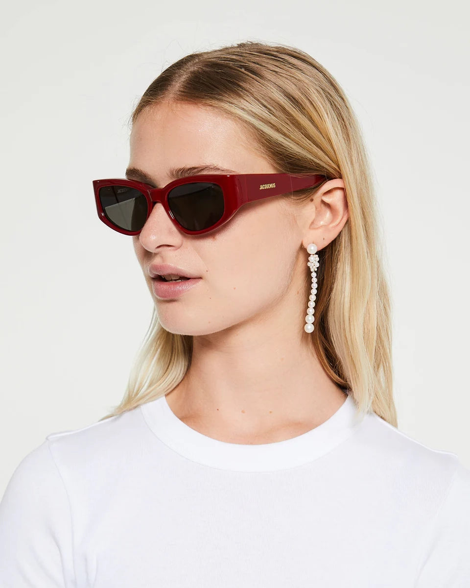 Blonde woman wearing Jaquemus Gala Sunglasses in Burgundy with plain white tee