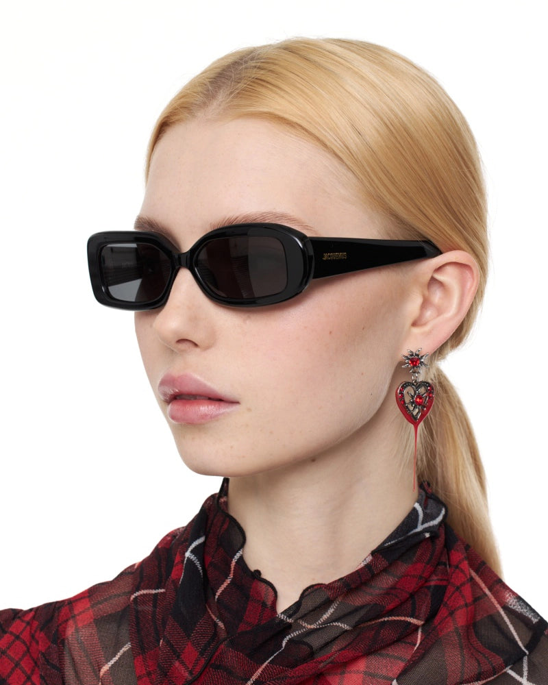 Woman wearing Jaquemus Rond Carre Sunglasses in Black with gold detail and plaid shirt