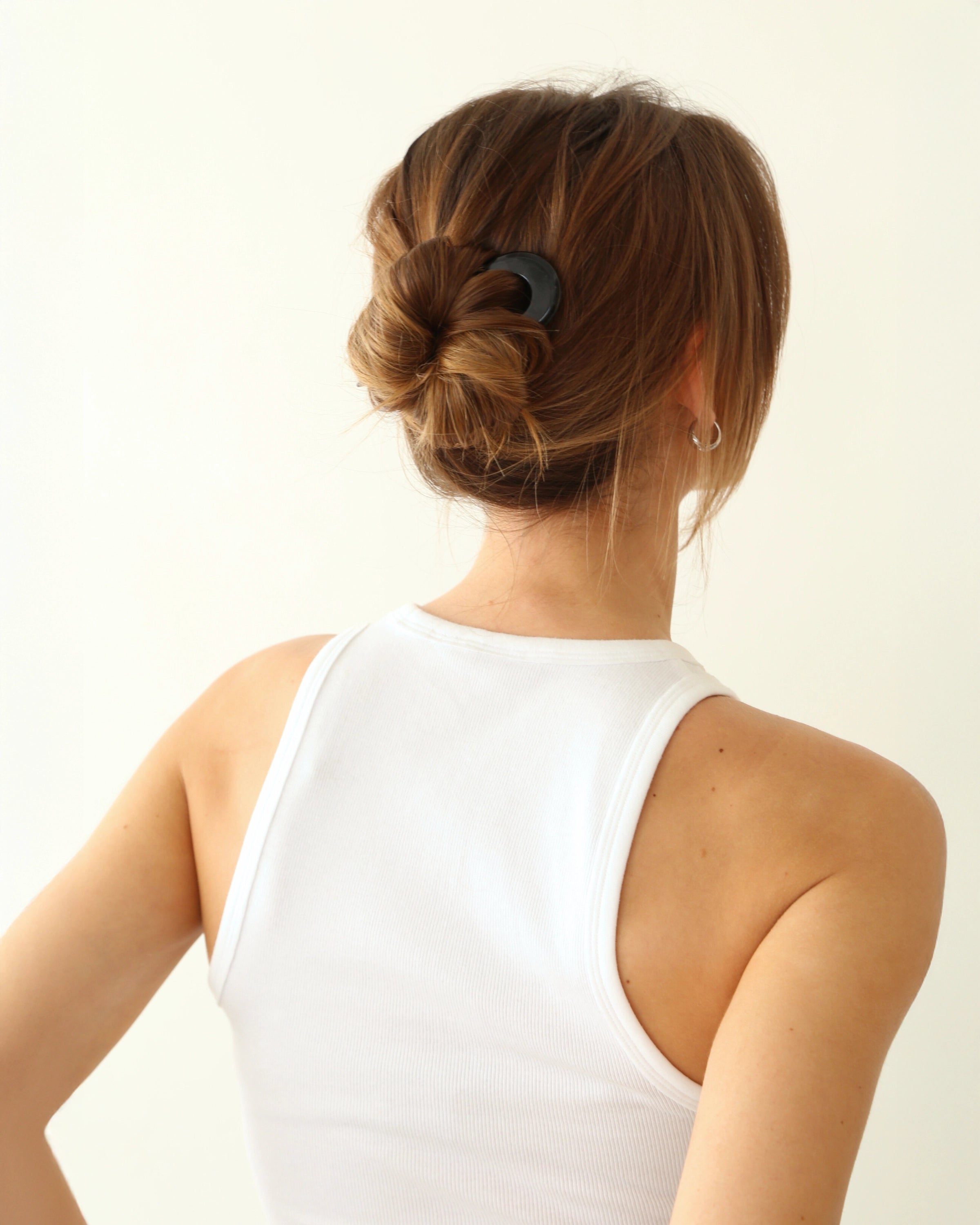 Person with a bun hairstyle with a french pin in black in her hair