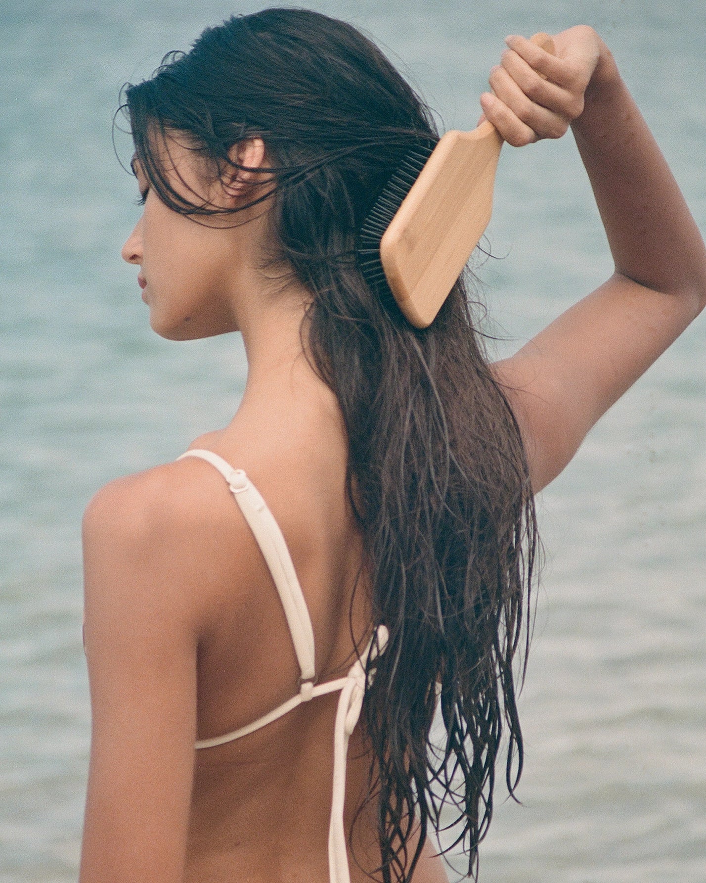 Woman combing her hair with a bamboo wooden hairbrush