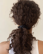 Curly hair tied back with a black silk scrunchie
