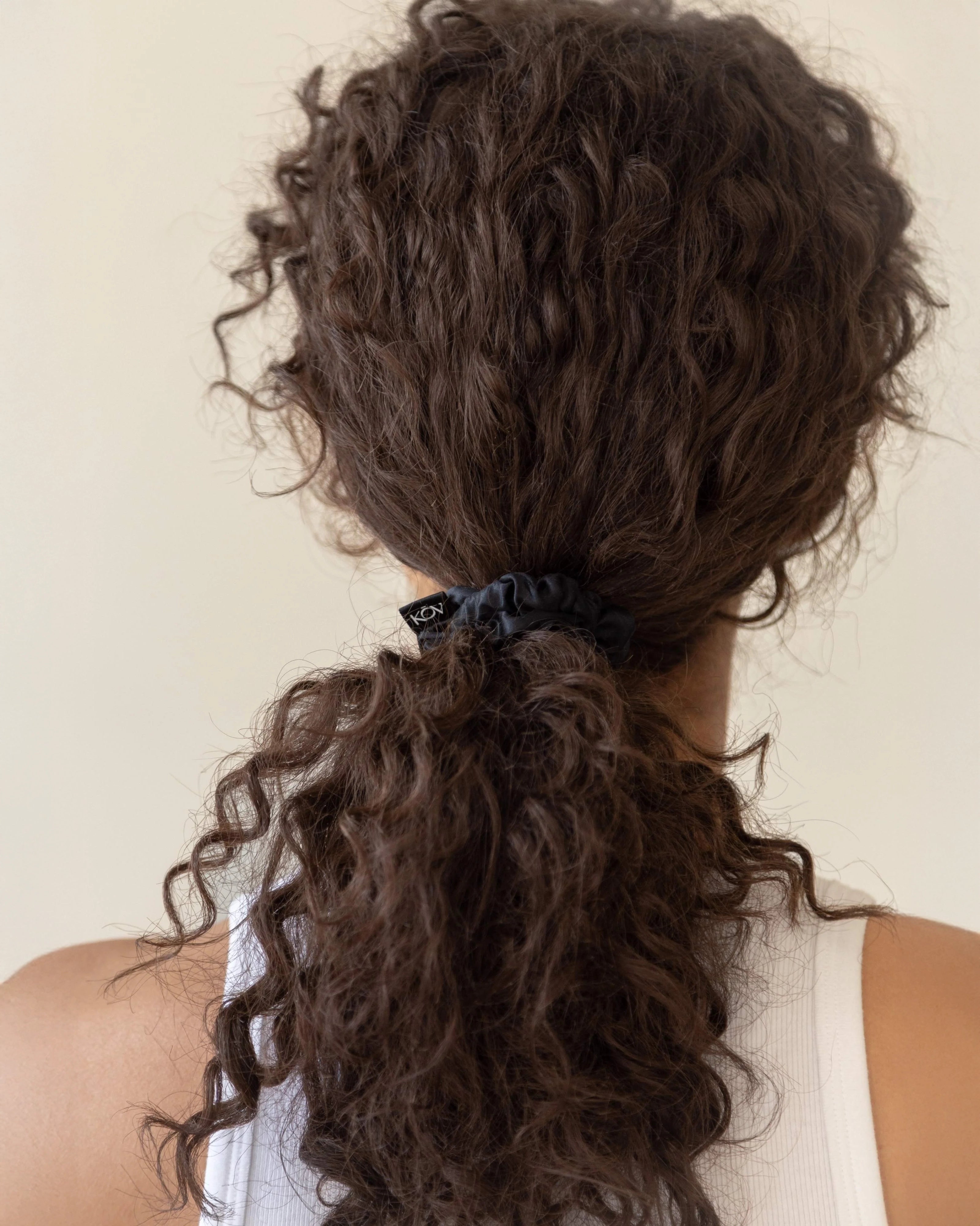 Curly hair tied back with a black silk scrunchie