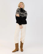 Woman wearing a fairisle sweater in blavk with cream accents