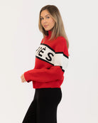 Woman wearing a red sweater with black and white accents with 'Après' on it
