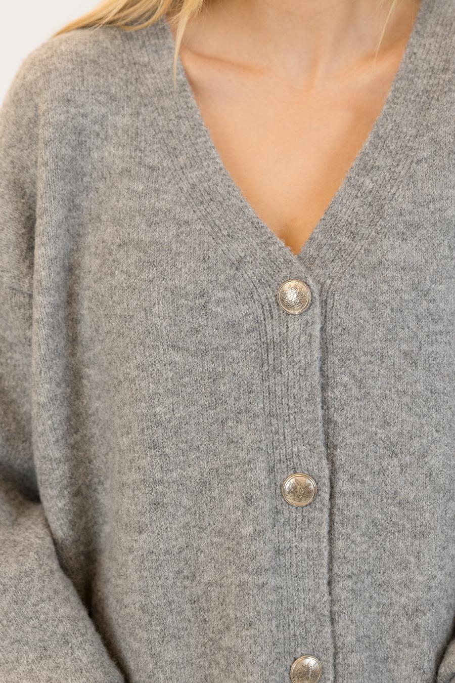 close up details of silver buttons on a grey cardigan