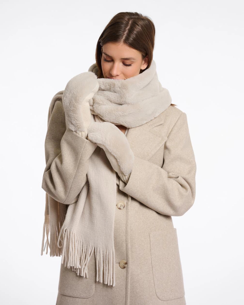 Woman wearing beige faux fur gloves with matching coat and scarf