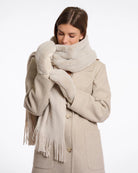 Woman wearing beige faux fur gloves with matching coat and scarf