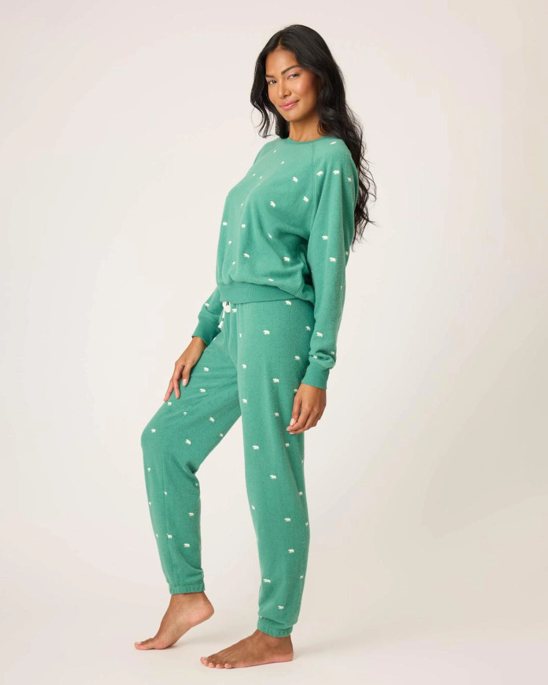 Woman wearing a green pajama set with white bears embroidered all over