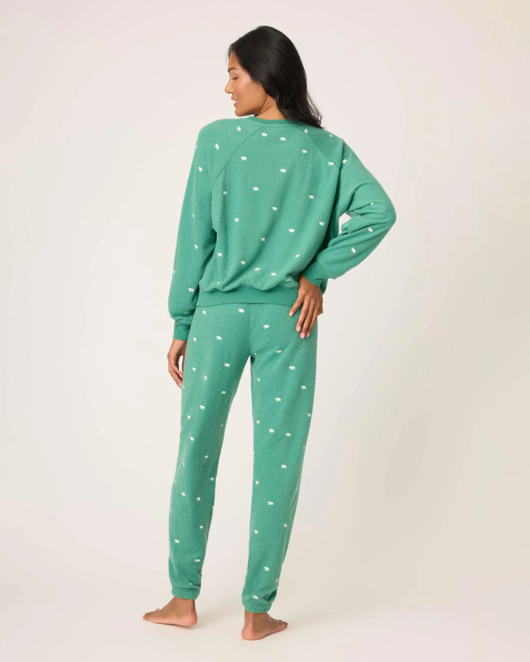 Woman wearing a green pajama set with white bears embroidered all over