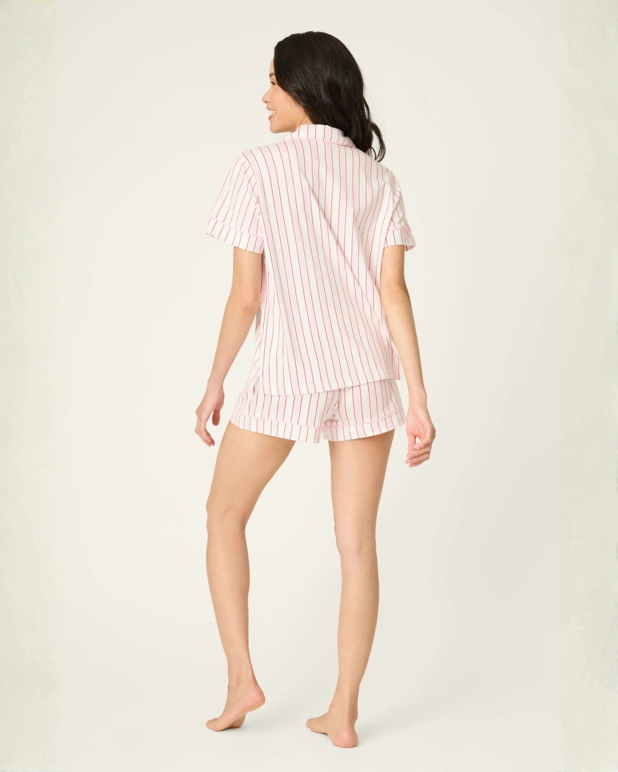 a woman wears a short sleeve and shorts and eye mask pj set in pink with red stripes
