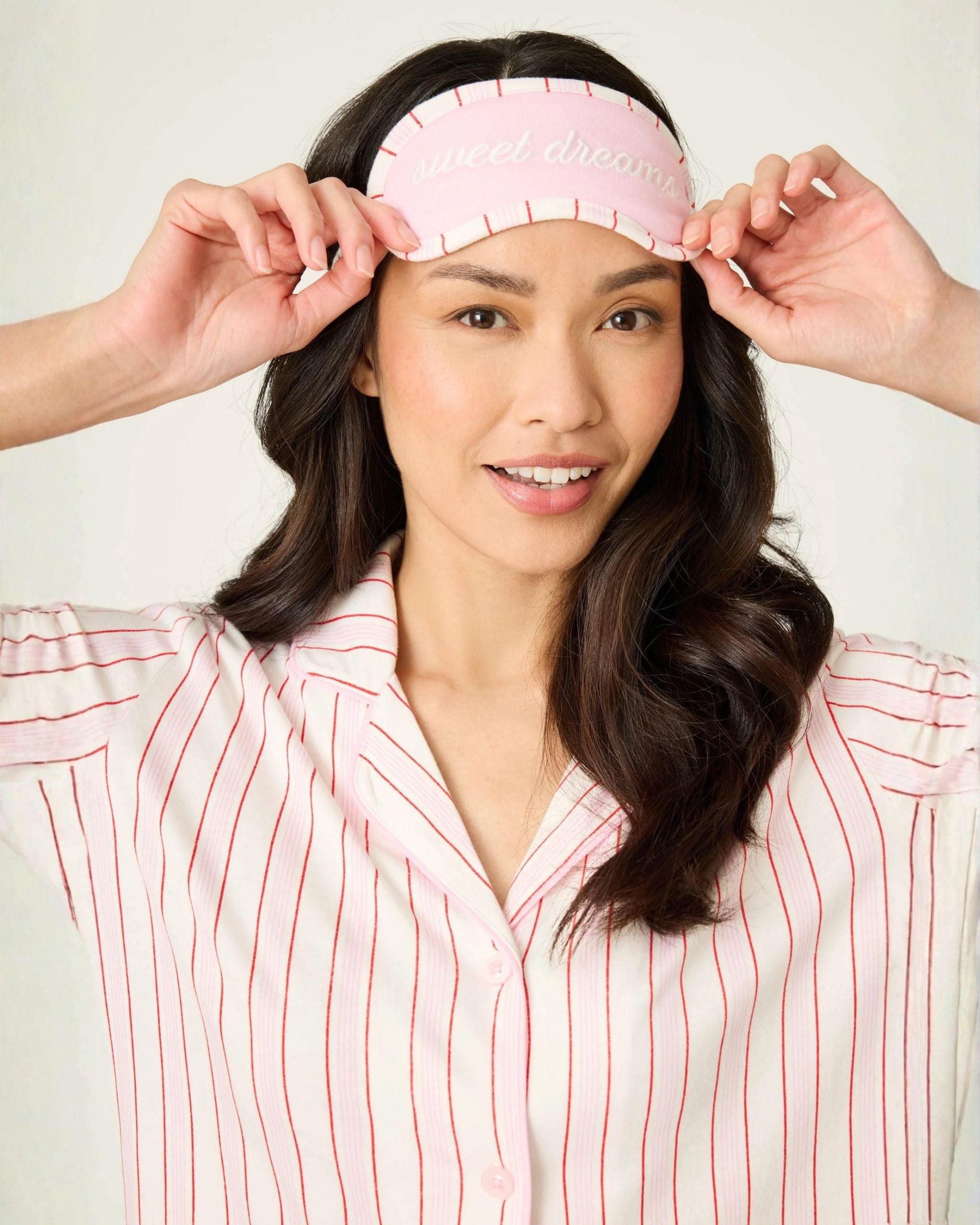 a woman wears a short sleeve and shorts and eye mask pj set in pink with red stripes