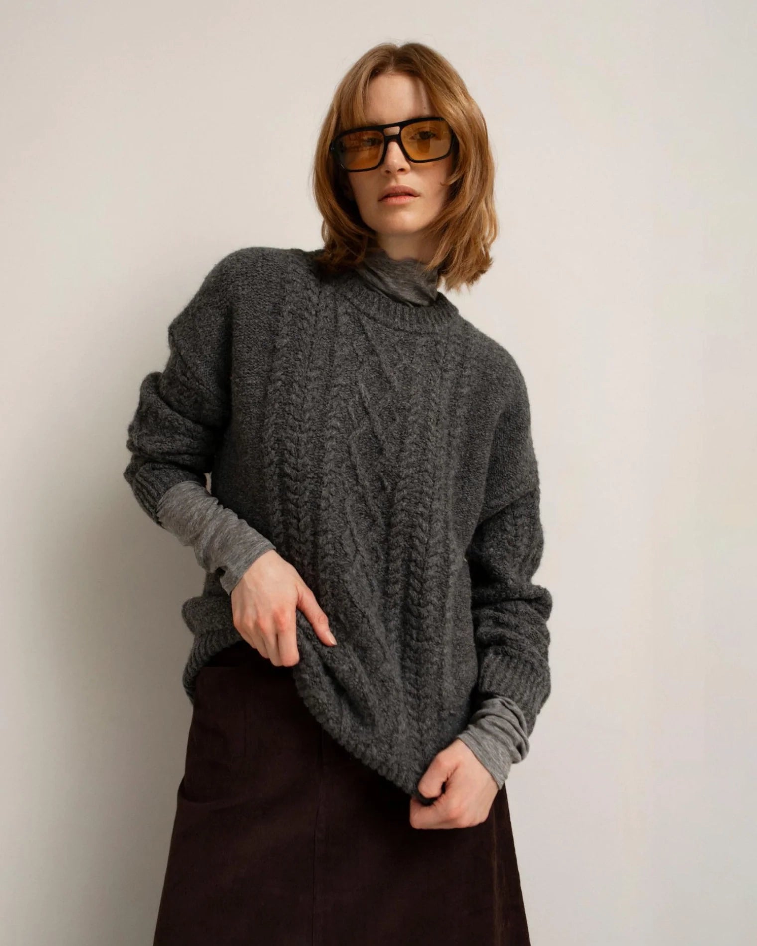 a woman wearing a gray cable knit sweater