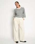 woman wearing a striped knit sweatshirt in cream and grey stripes