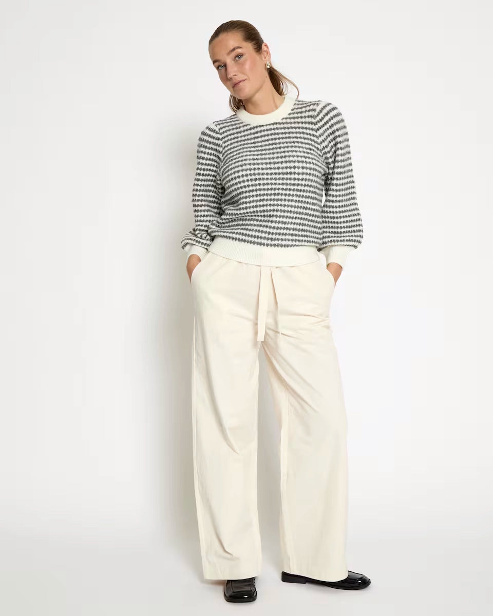 woman wearing a striped knit sweatshirt in cream and grey stripes