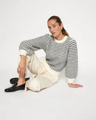 woman wearing a striped knit sweatshirt in cream and grey stripes
