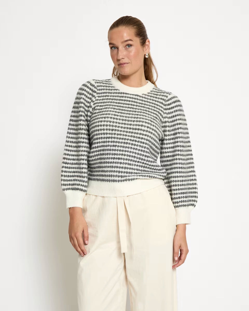woman wearing a striped knit sweatshirt in cream and grey stripes