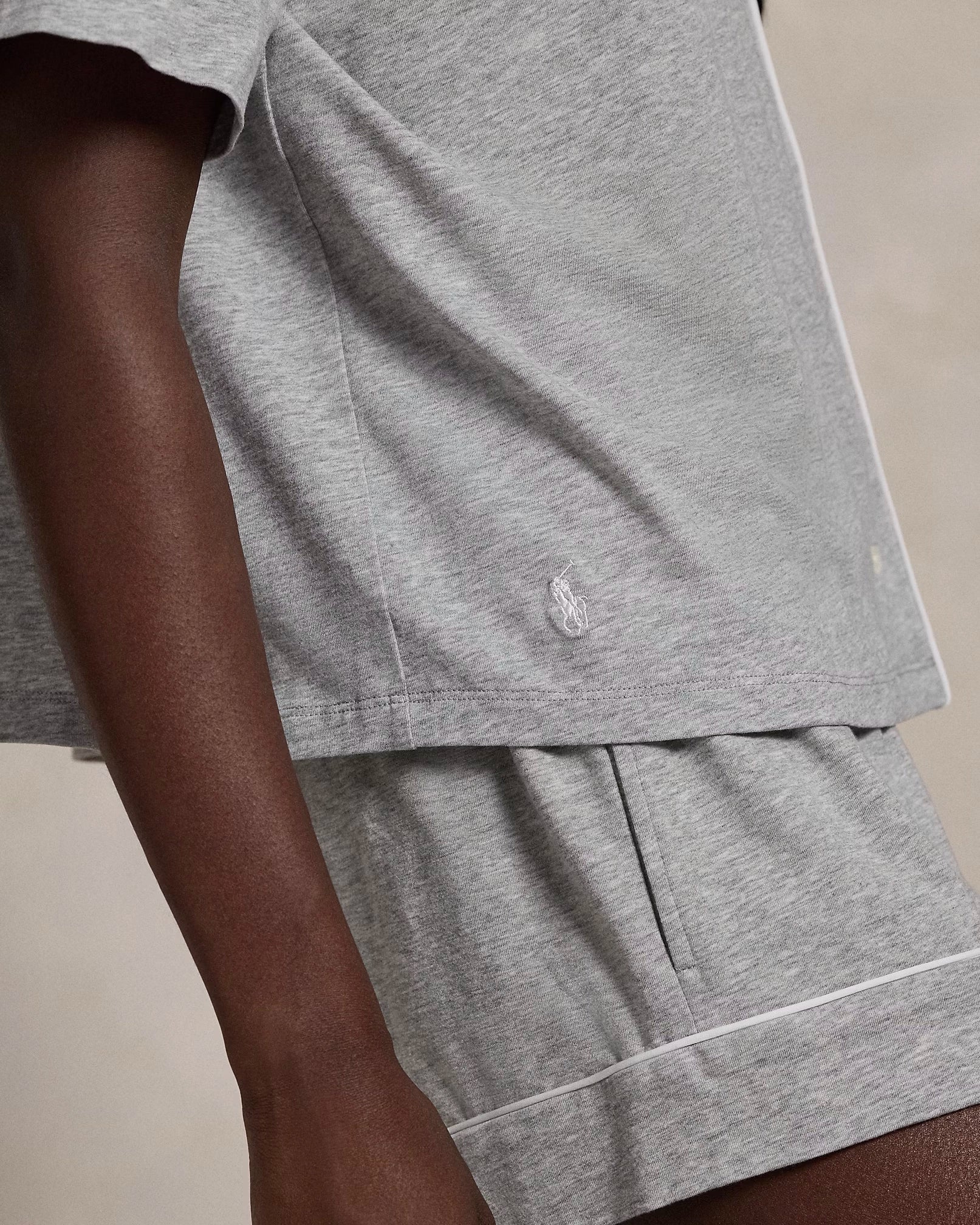 A model wearing a short-sleeve and short pajama set in heather grey with contrast piping and a signature embroidered Pony on the chest.