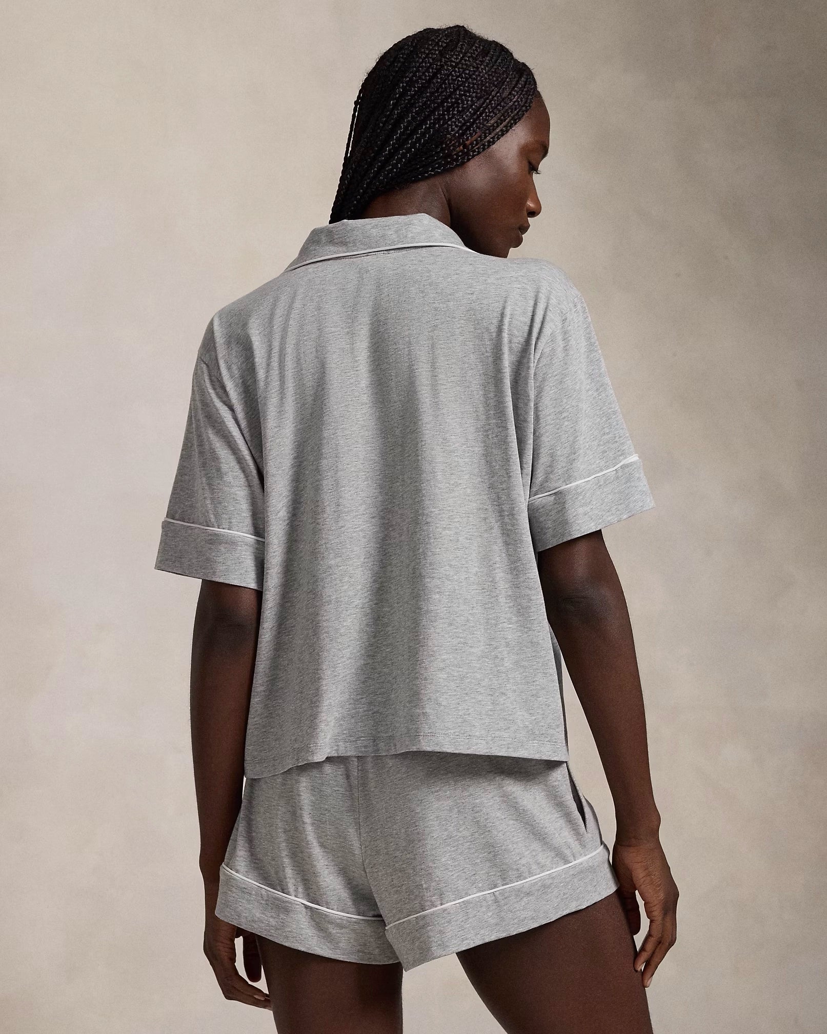A model wearing a short-sleeve and short pajama set in heather grey with contrast piping and a signature embroidered Pony on the chest.