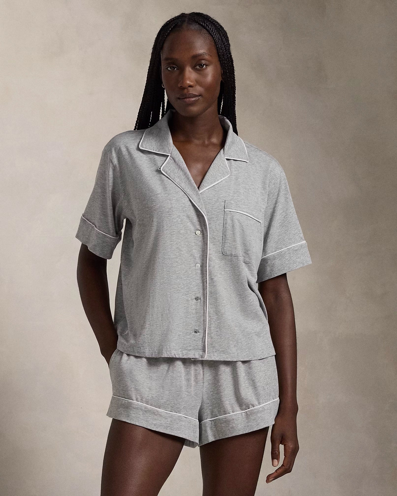 A model wearing a short-sleeve and short pajama set in heather grey with contrast piping and a signature embroidered Pony on the chest.