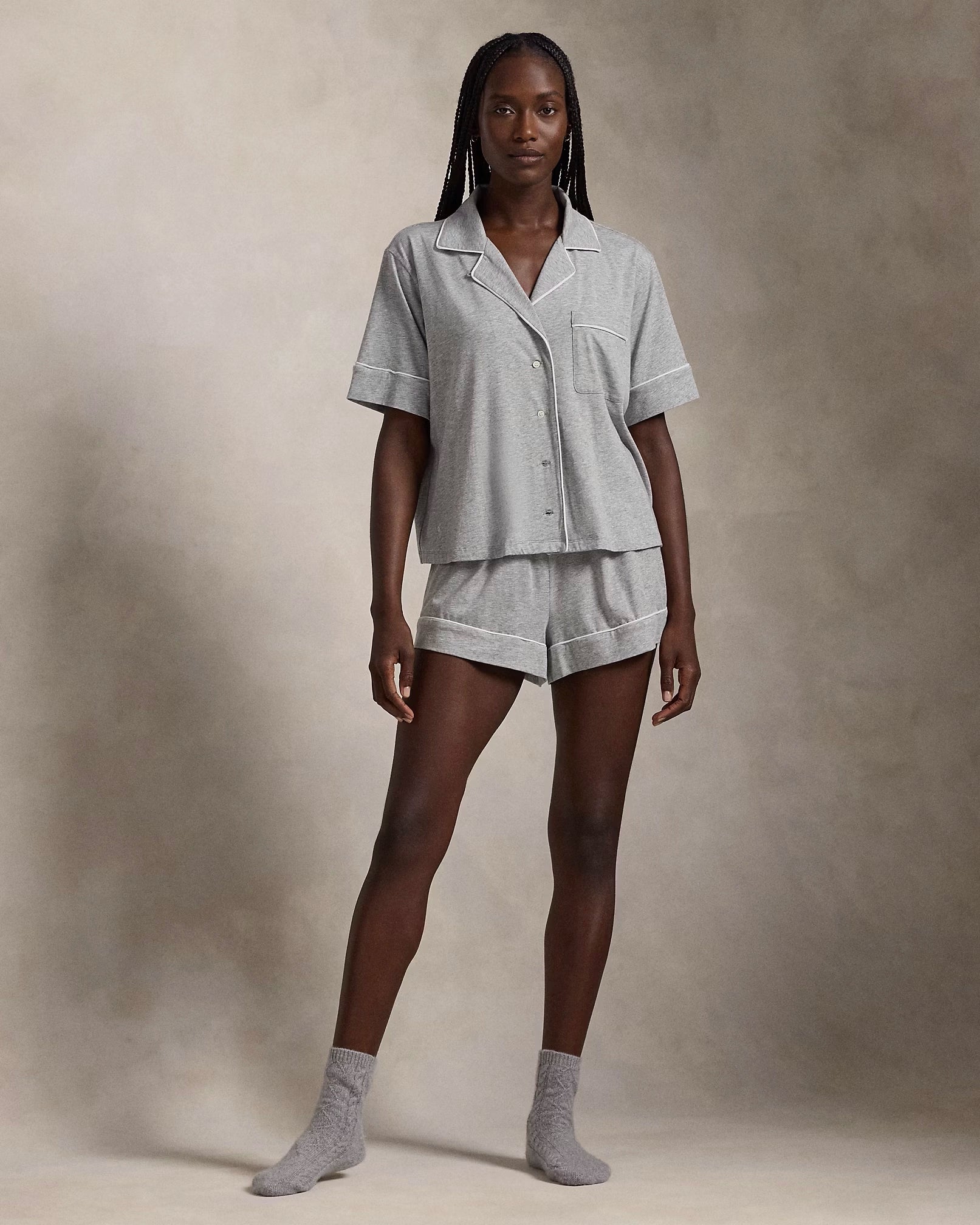 A model wearing a short-sleeve and short pajama set in heather grey with contrast piping and a signature embroidered Pony on the chest.