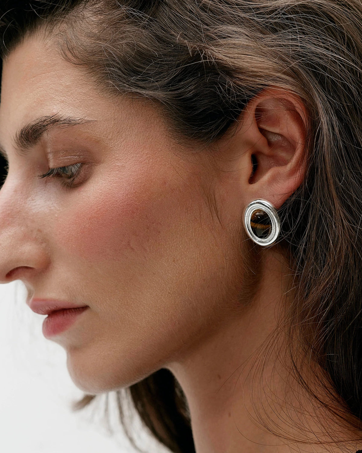 large silver oval earring with brown stone in the middle