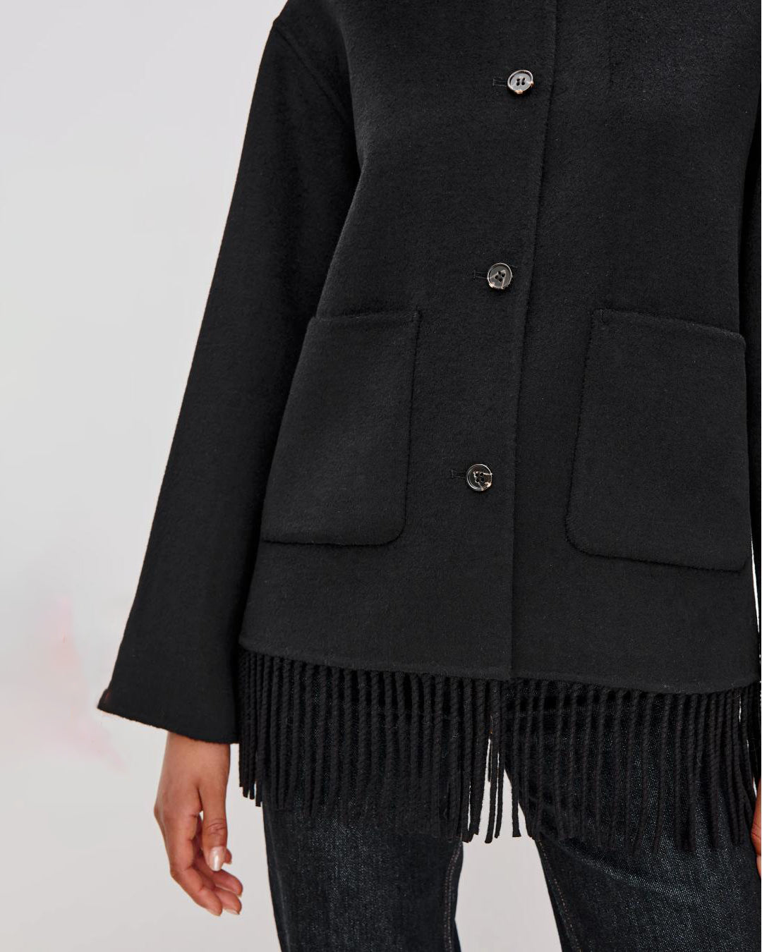 Person wearing a black jacket with fringes on the hem
