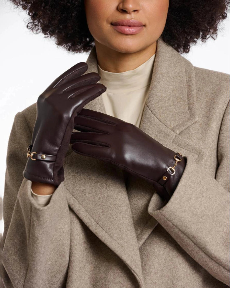 a woman wears a pair of faux leather gloves in dark brown with a gold horsebit detail on the wrist
