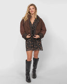 Woman wearing a brown teddy jacket over a floral dress