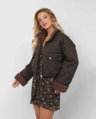 Woman wearing a brown quilted jacket over a floral dress