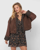 Woman wearing a brown teddy jacket over a floral dress