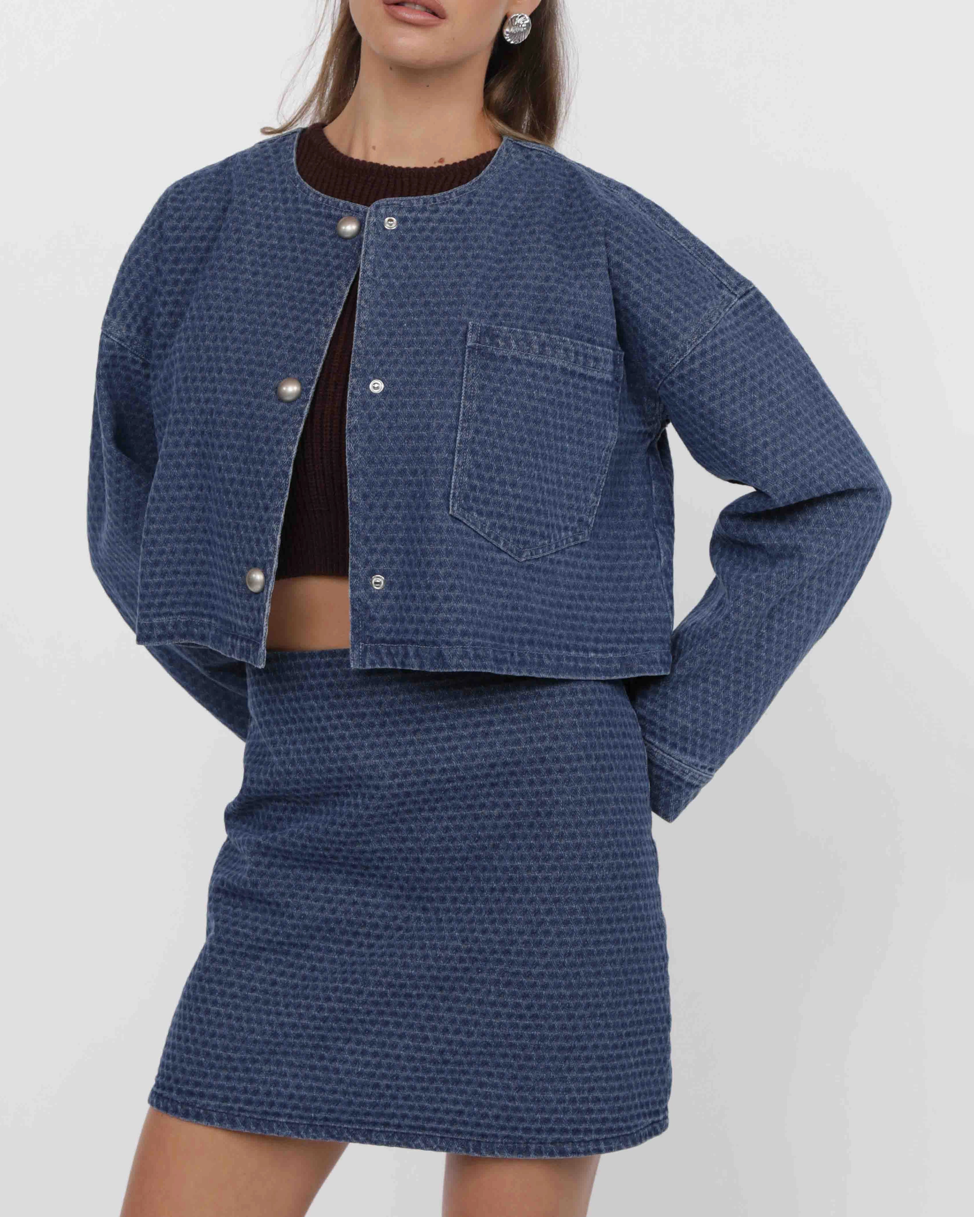woman wearing a blue textured denim jacket and skirt set