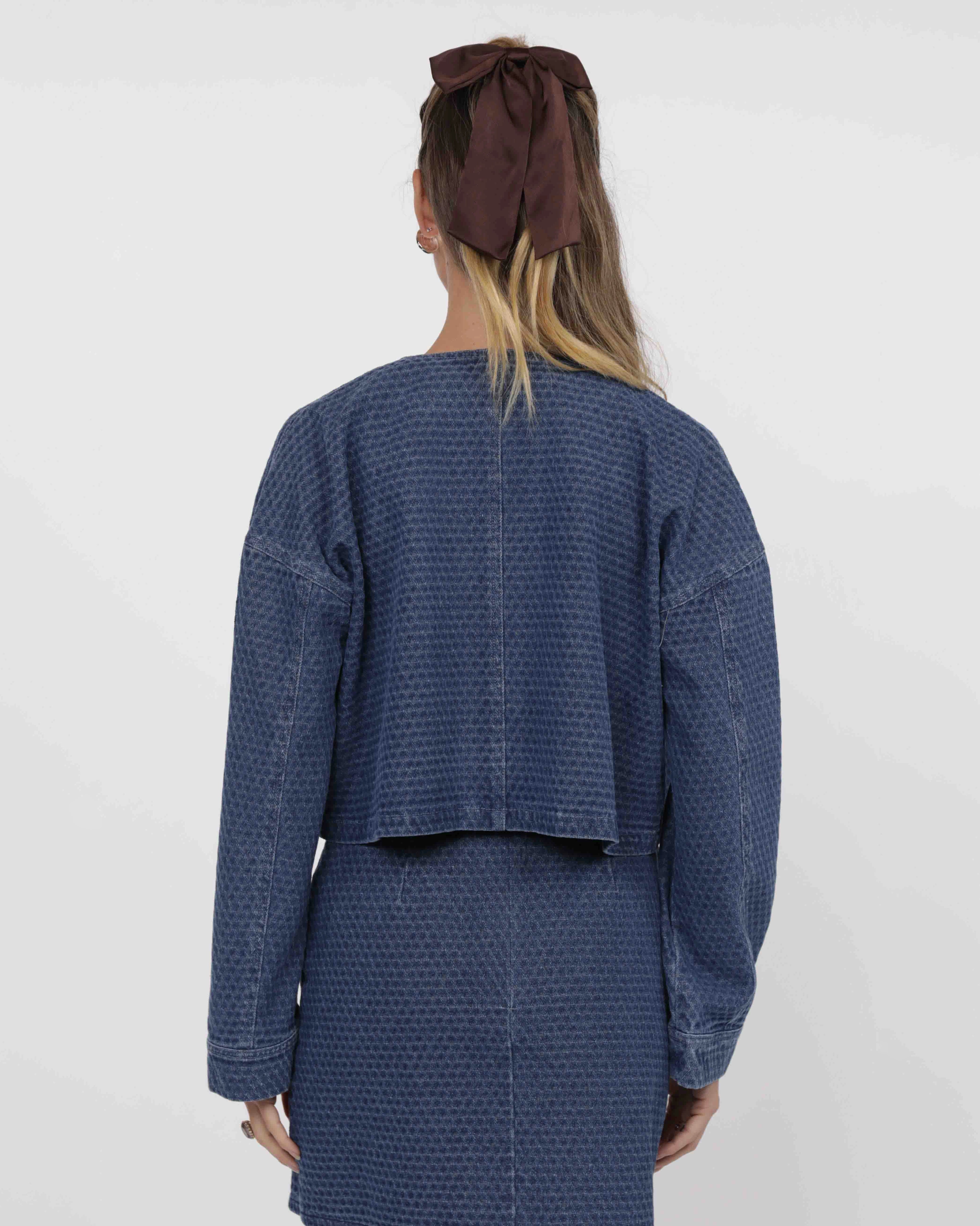 woman wearing a blue textured denim jacket and skirt set