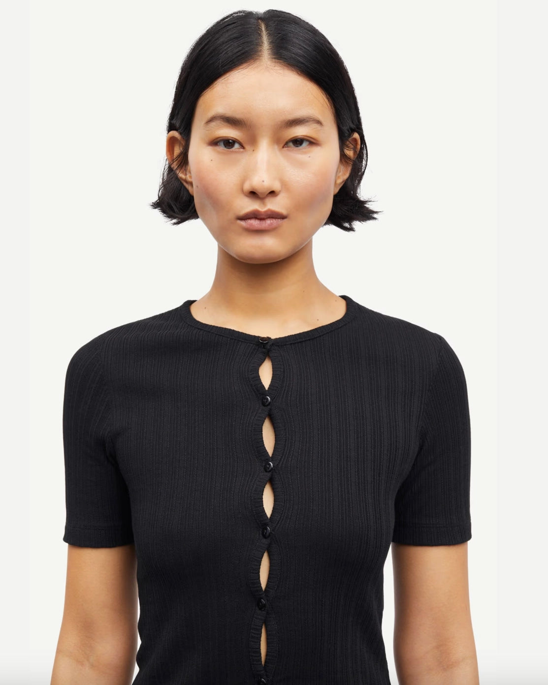 Woman wearing a black short-sleeve button down cardigan top