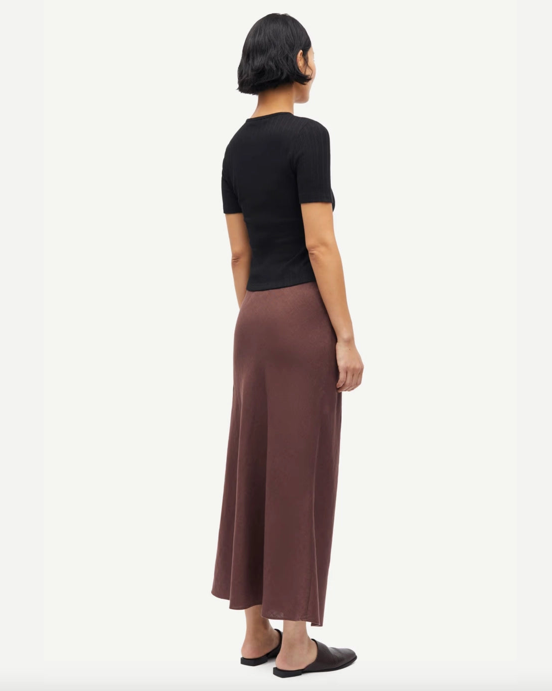 Woman wearing a black short-sleeve button down cardigan top and brown skirt