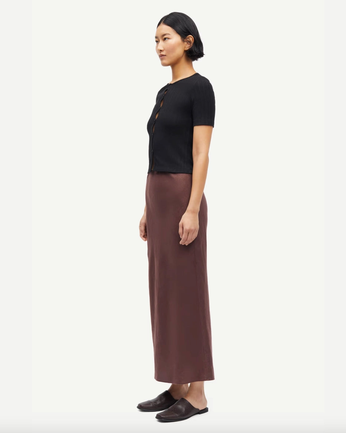 Woman wearing a black short-sleeve button down cardigan top and brown skirt