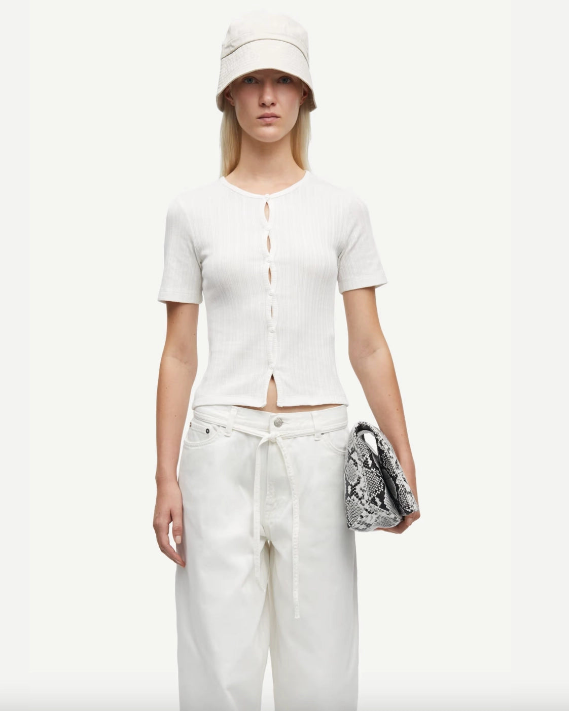 Woman wearing a white short-sleeve button down cardigan top and white pants