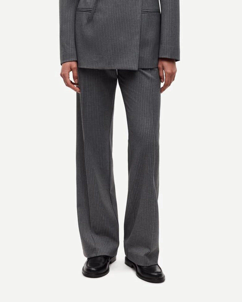 Person wearing a gray pinstripe suit trousers