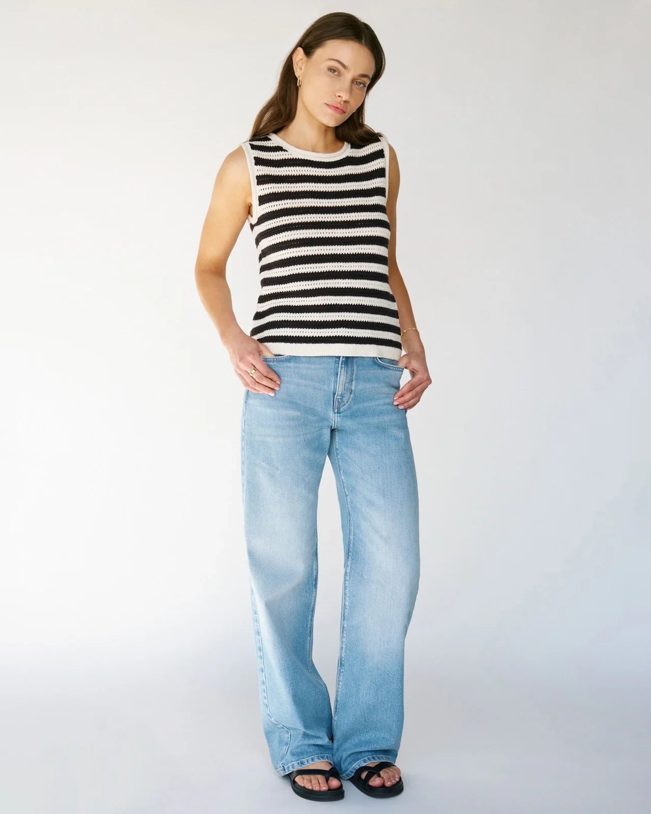 Woman wearing a crochet knit black and white striped sleeveless top with jeans
