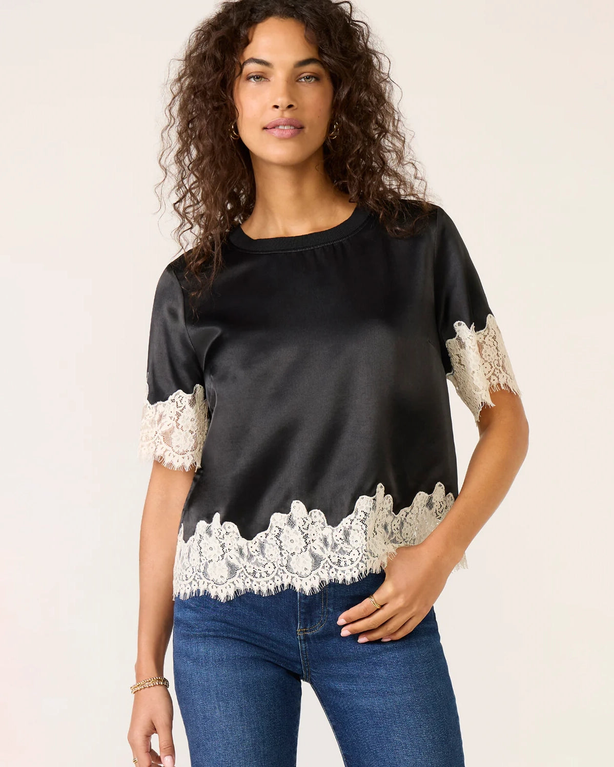 a woman weard a black short sleeve top with cream lace on the bottom and on the sleeves