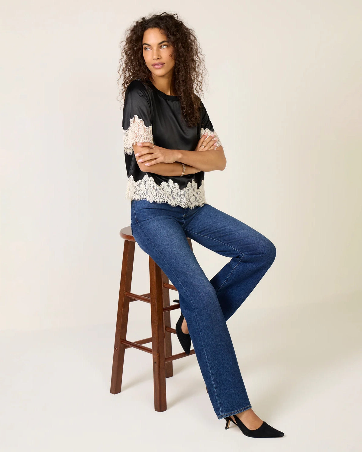 a woman weard a black short sleeve top with cream lace on the bottom and on the sleeves