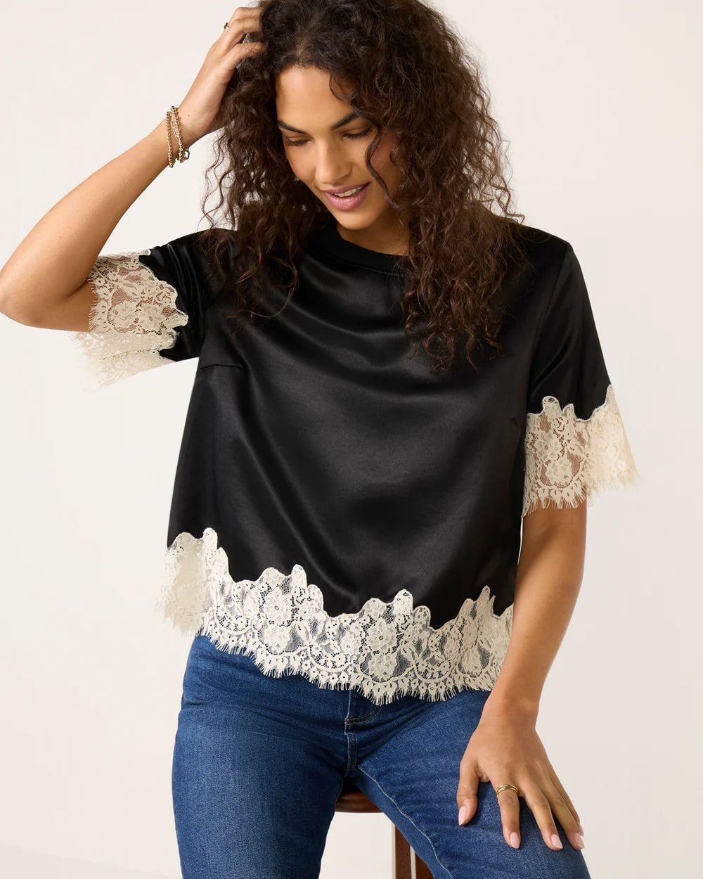 a woman weard a black short sleeve top with cream lace on the bottom and on the sleeves