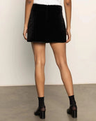 a woman wearing a quilted velvet mini skirt in black