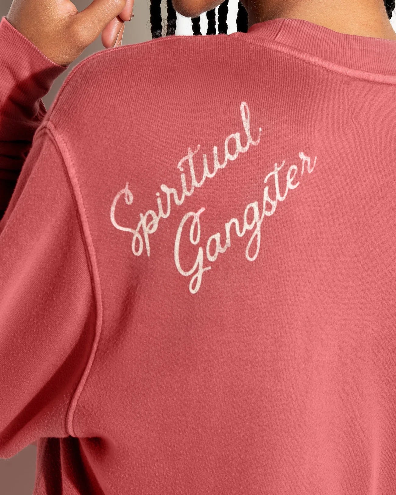 Woman wearing a rust coloured sweatshirt with 'Spiritual Gangster' branding