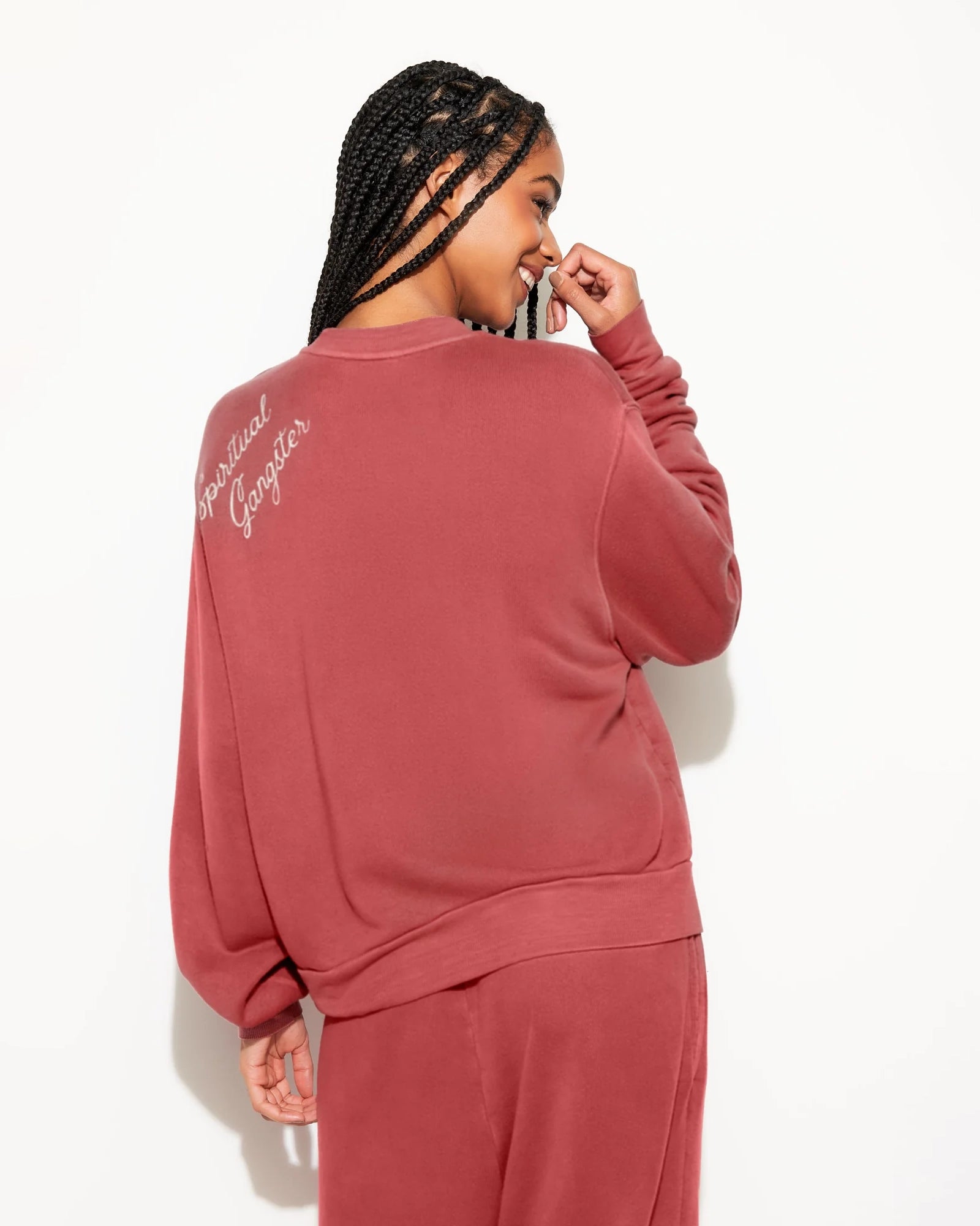 Woman wearing a rust coloured sweatshirt with 'Spiritual Gangster' branding