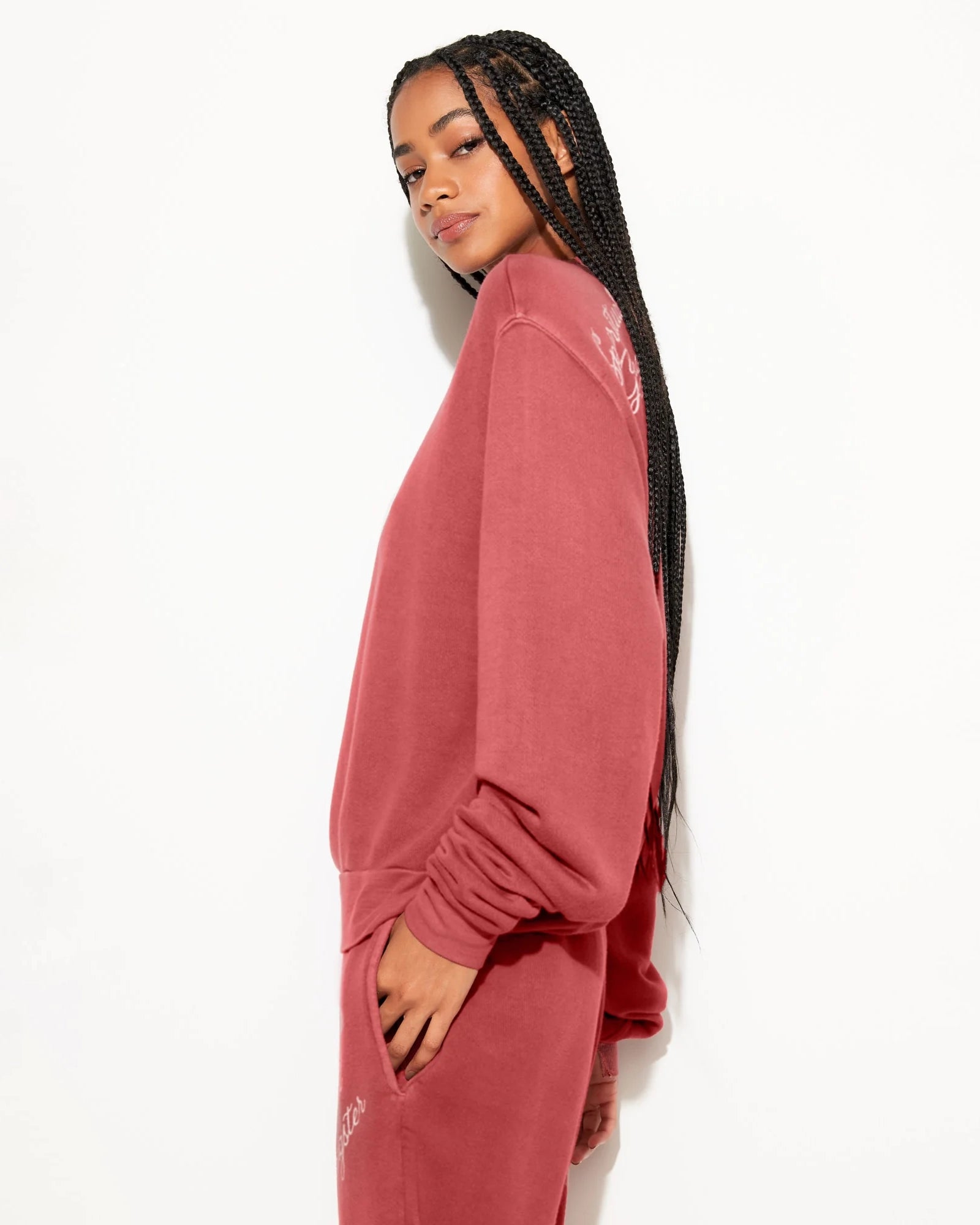 Woman wearing a rust coloured sweatshirt with 'Spiritual Gangster' branding