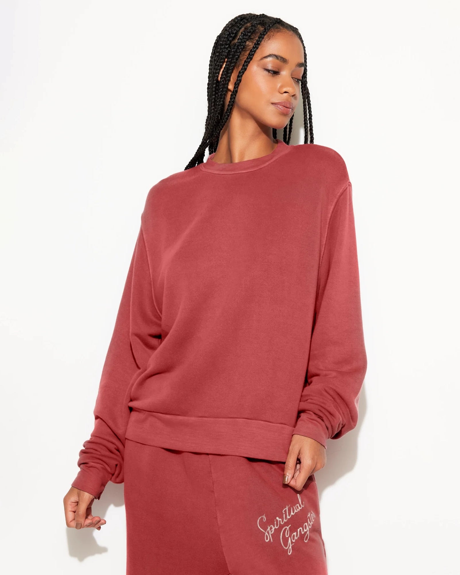Woman wearing a rust coloured sweatshirt with 'Spiritual Gangster' branding