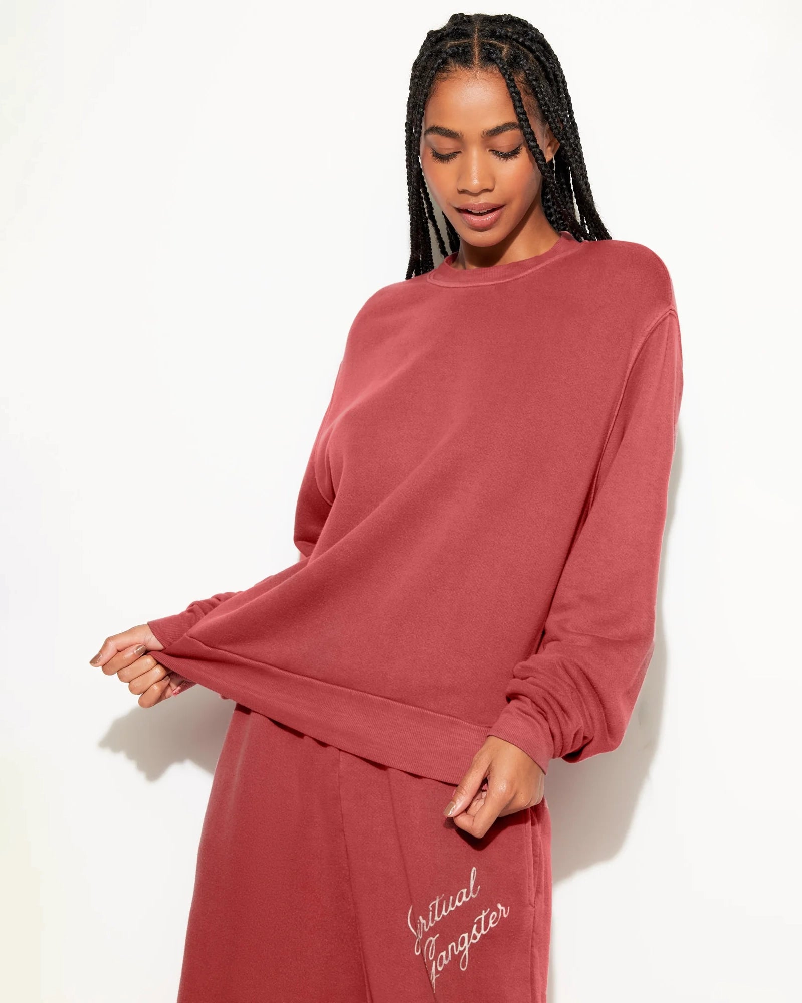 Woman wearing a rust coloured sweatshirt with 'Spiritual Gangster' branding