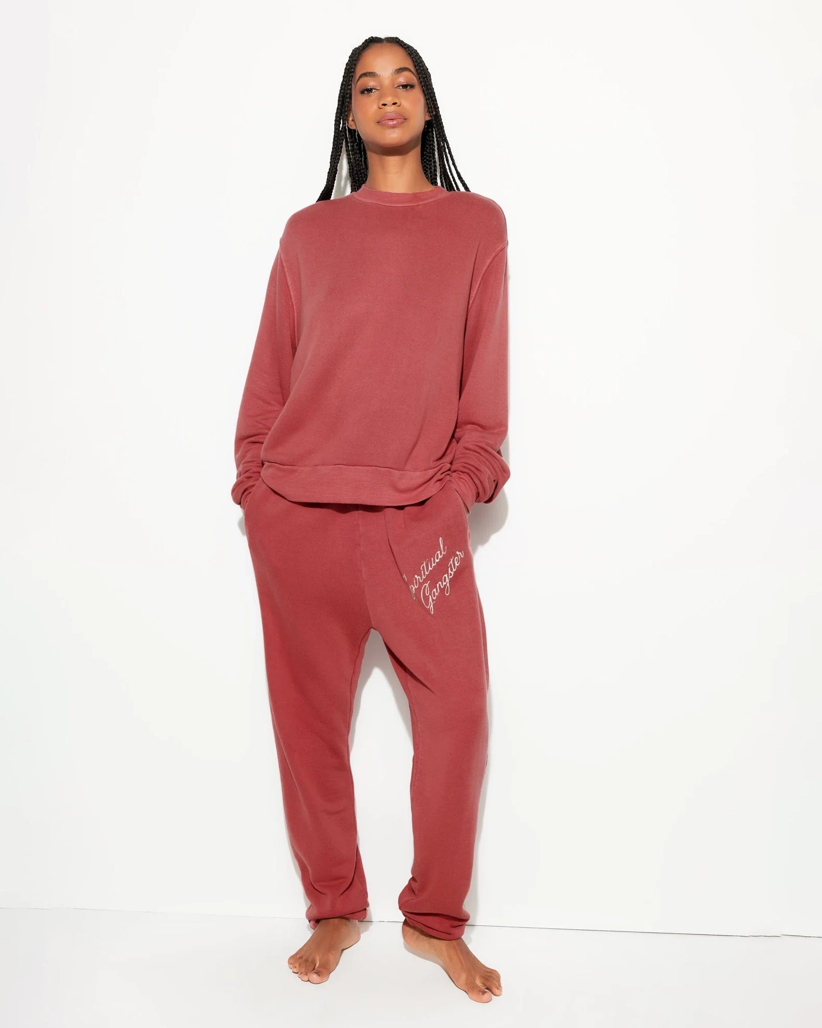 Woman wearing a rust coloured sweatshirt and matching sweatpants with 'Spiritual Gangster' branding