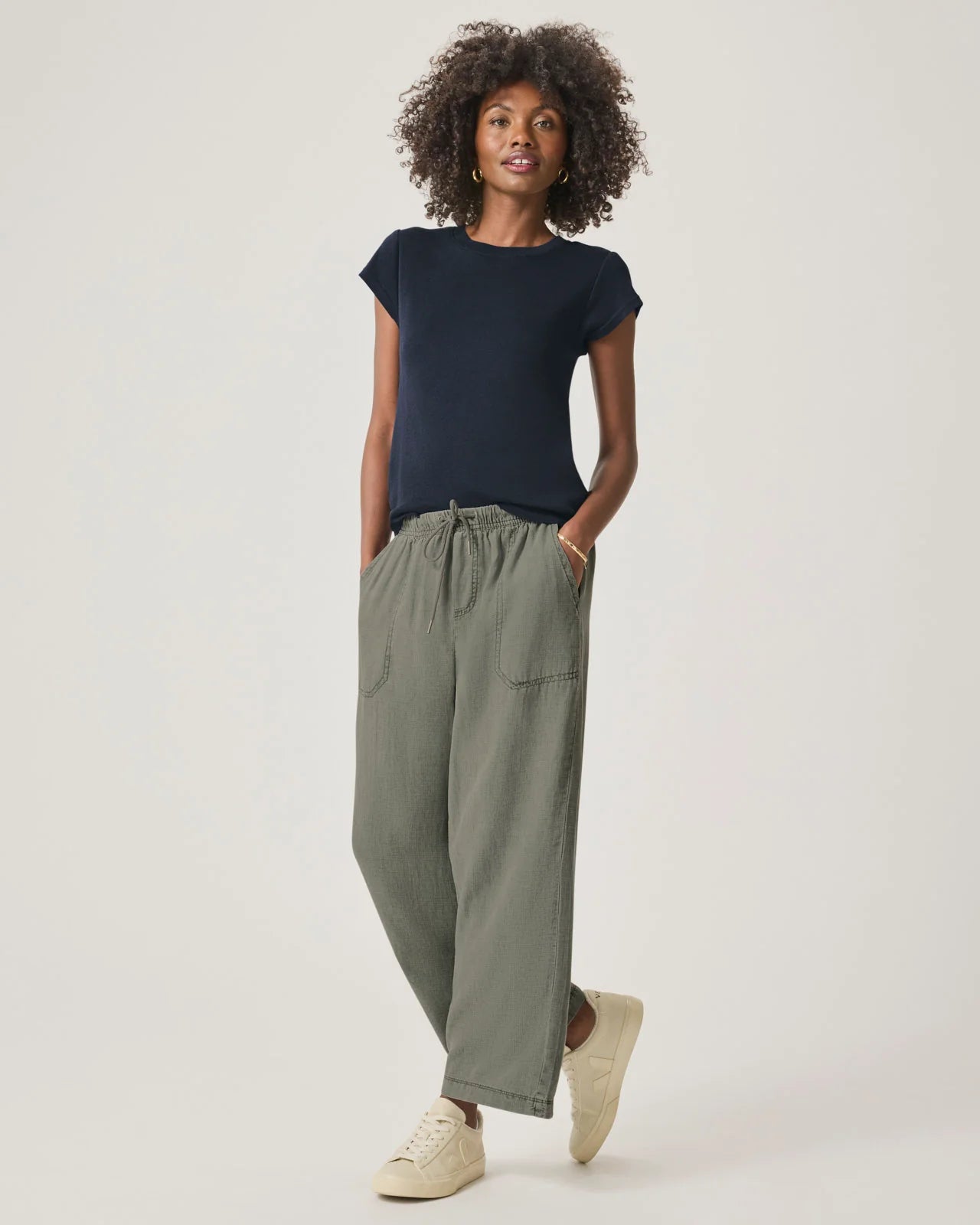 a woman wearing a classic crew neck navy tshirt with green drawstring trousers