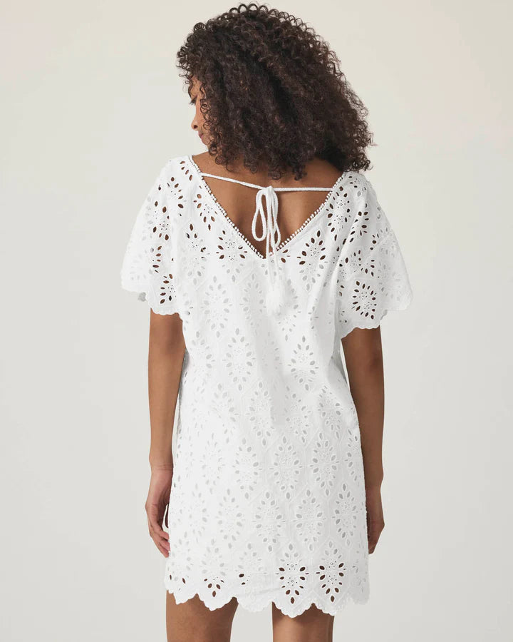 Woman wearing a white lace eyelet cotton dress with a tie between shoulders